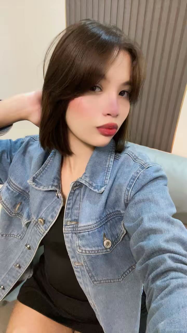 A woman from Venezuela in a denim jacket holding her camera at arm’s length for a cam to cam chat