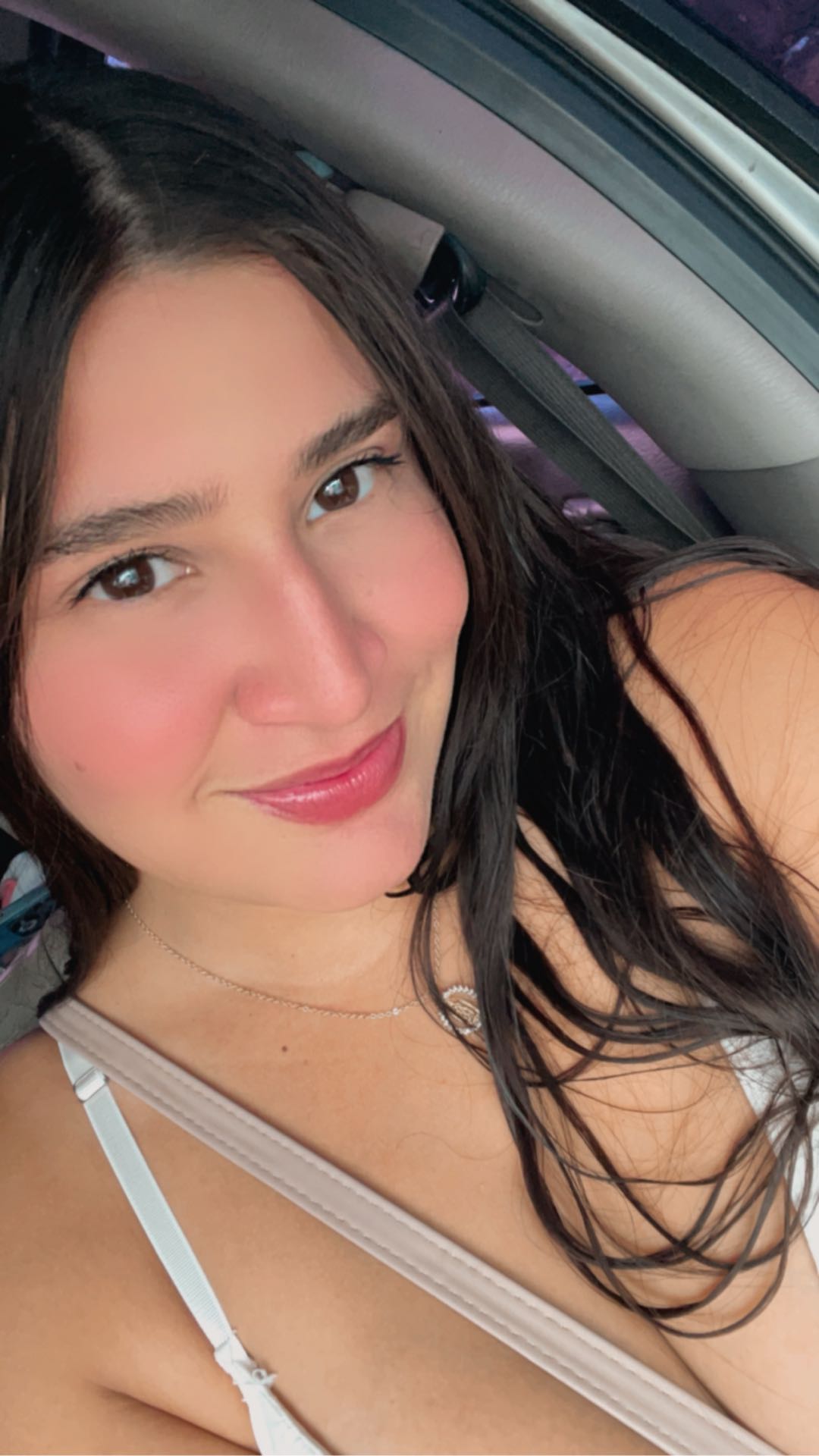 A woman from Venezuela smiling in a car, opening CamlooCam from her phone’s home screen