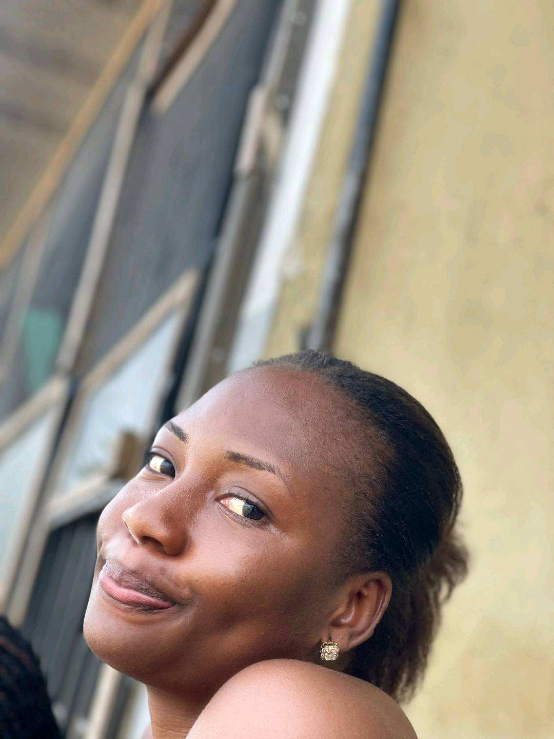 A smiling woman from Nigeria glancing over her shoulder, the kind of face a random cam chat can bring up